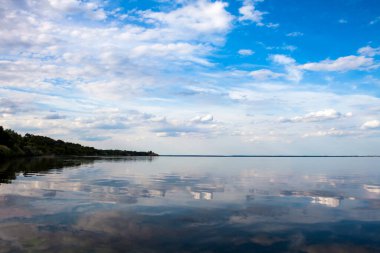 Güzel mavi bulutlu akşam gökyüzü ve onun sudaki yansıması.