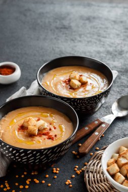 Kırmızı biberli mercimek kremalı çorba ve koyu arkaplanda siyah seramik kaseler. Boşluğu kopyala
