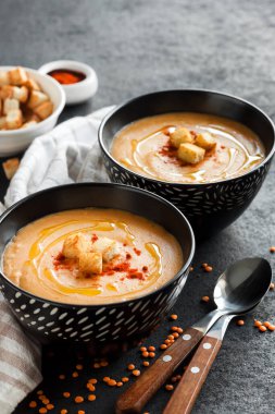 Kırmızı biberli mercimek kremalı çorba ve koyu arkaplanda siyah seramik kaseler. Boşluğu kopyala