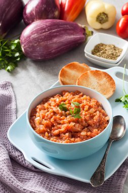 Mavi kasede patlıcan havyarı ve arka planda taze sebzeler..