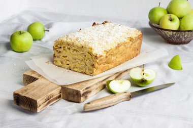 Elmalı ve hindistancevizli pasta ahşap kesim tahtası ve vazoda elmalar