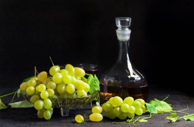 Meyve kasesinde taze üzümler ve siyah arka planda üzüm suyu ile sürahi. Boşluğu kopyala