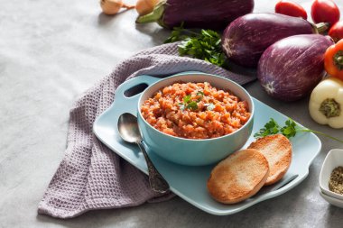 Mavi kasede patlıcan havyarı ve arka planda taze sebzeler..