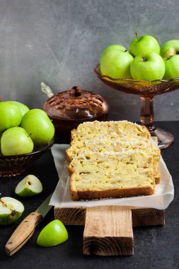 Dilimlenmiş elma ve hindistancevizli hödük, arka planda tahta kesme tahtasının üzerinde.