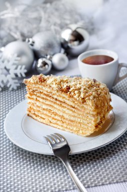 Bir dilim kremalı pasta ve arka planda Noel topları olan bir tabakta ceviz.