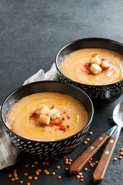 Kırmızı biberli mercimek kremalı çorba ve koyu arkaplanda siyah seramik kaseler. Boşluğu kopyala