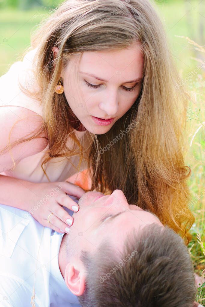 Girl and man couple laying down on a lawn and look to each others eyes