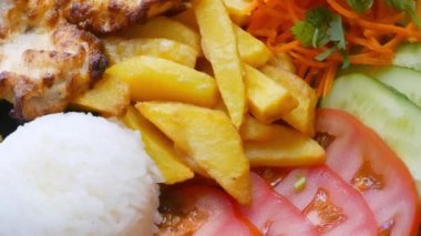 Bir tabakta kızarmış patates, biftek, domates ve pilav.
