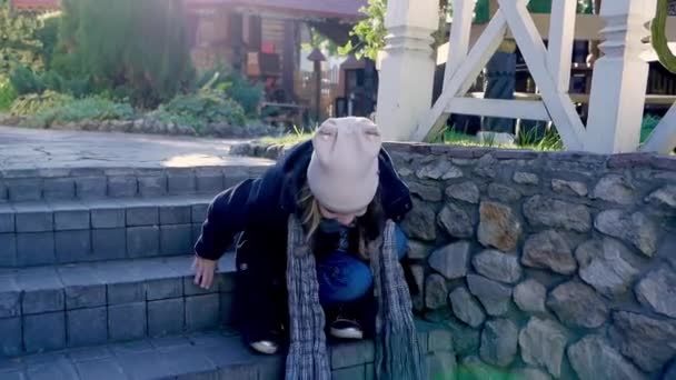 Gadis bahagia anak duduk turun ke tangga di taman musim gugur — Stok Video