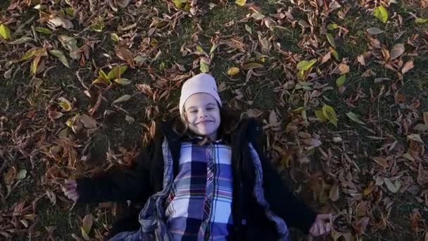 Jong kind meisje maakt engel vleugels in een herfst park — Stockvideo