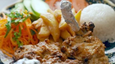Kızarmış et, patates, pirinç ve sebze salatası.