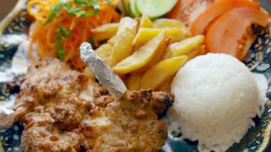 Kızarmış et, patates, pirinç ve sebze salatası.