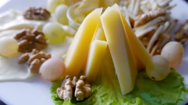 Kaasschotel, geserveerd met verschillende soorten kaas, honing, walnoten en druiven — Stockvideo