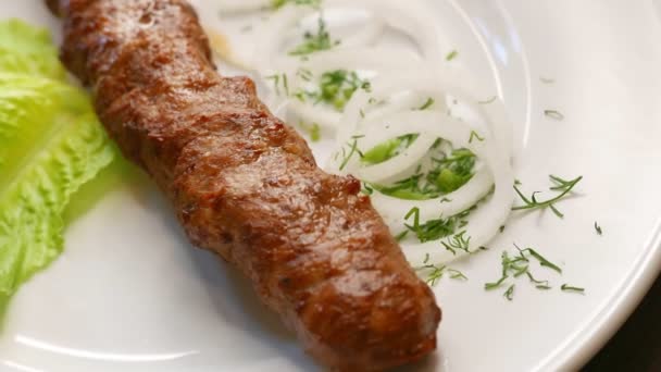 Carne de boi kebab girando em uma placa branca — Vídeo de Stock