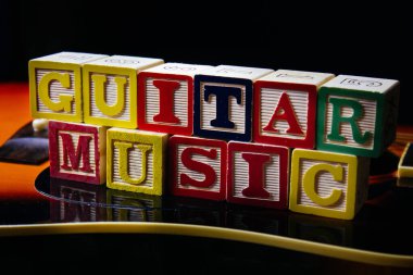 Gitarın üzerinde duran, harf küpleriyle yapılmış Gitar müziği..