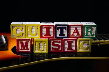 Gitarın üzerinde duran, harf küpleriyle yapılmış Gitar müziği..