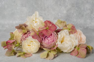 Gri bir arka planda gül ve ortancaların yakın plan çiçek düzenlemesi