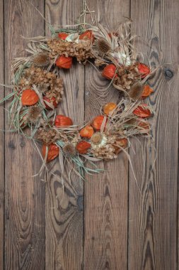  Ahşap bir arka planda doğal malzemelerden kurumuş çiçek çelengi. Şükran Günü Konsepti.
