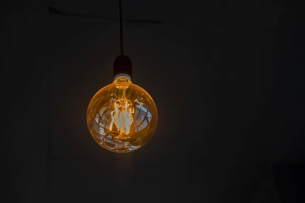 Gloeilamp op een zwarte achtergrond. Warm zacht licht, het concept van gezelligheid en creativiteit. — Stockfoto