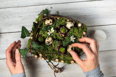 A faceless Caucasian woman creates an Easter composition, plants hyacinth bulbs on a white wooden background. Eco-friendly lifestyle. view from above 