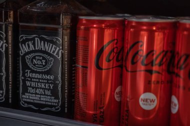 Lviv, Ukraine, January 2022, a bottle of Jack Daniel's Whiskey and cans of Coca-Cola in the Silpo supermarket on the shelf. Blur and selective focus. Blurred foreground