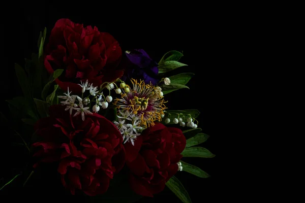Still life. luxury dark red peonies and other spring flowers on a black background. Moody flowers. Copy space and color bloom. Loy key photo