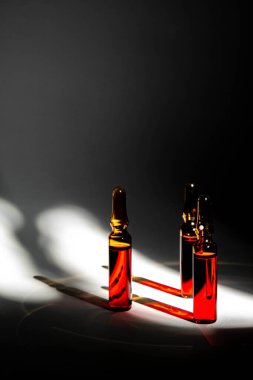 injections of B vitamins. Ampoules with red liquid on a gray background. Beauty and health concept. copy space. Blur and selective focus