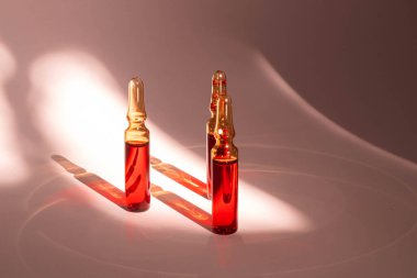 injections of B vitamins. Ampoules with red liquid on a peachy background. Beauty and health concept. copy space. Blur and selective focus