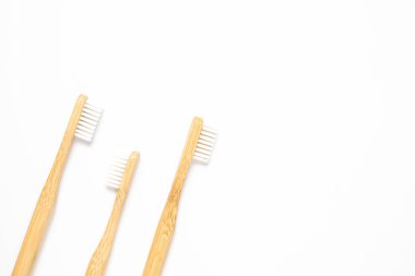 Three wooden toothbrushes on a white background, top view. Zero waste concept and copy space. 