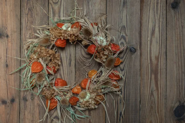 Koyu ahşap arka planda doğal malzemelerden kurumuş çiçek çelengi. Sonbahar evi dekorasyonu. Şükran Günü Konsepti 