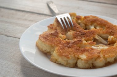 Ahşap bir masada, tabakta kızartılmış karnabahar şnitzeli. Vejetaryenlik kavramı. Bulanık arkaplan 