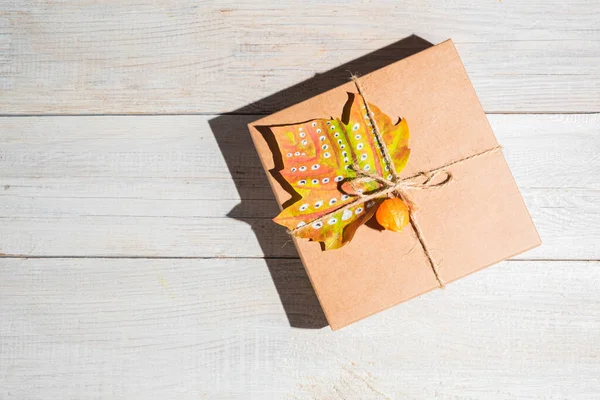 Craft gift box decorated autumn maple leaf. Thanksgiving and zero waste concept. Copy space