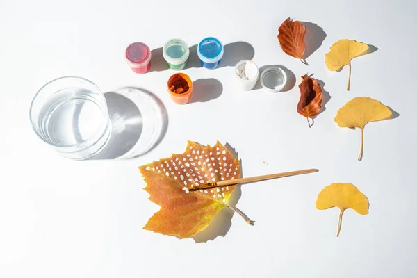 Painted autumn leaves on a white background. word Autumn is written on a leaf. Child creativity and zero waste concept