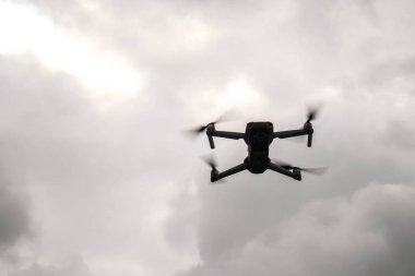 10 Eylül 2022, Karpat Dağları, Ukrayna. Siyah kuadrokopter Mavic gri bulutlu gökyüzüne doğru uçuyor. Bulanık ve seçici odaklanma 