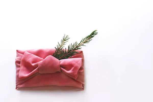 Kutu hediyesi, Furoshiki kumaşıyla sarılan güzel ve yeniden kullanılabilir ekolojik Japon teknolojisine göre paketlenmiştir. Noel ağacı dalı süs olarak. Sıfır atık kavramı. Beyaz arkaplanda boşluk ve düz konum kopyala