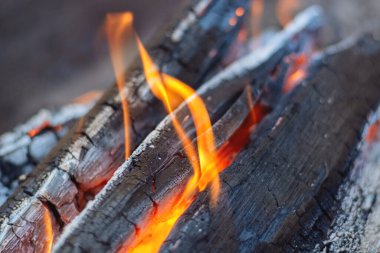 Şöminede odun yanıyor. Arka planda sıcak kırmızı bir ateşin alevleri. Sigaralar parlar ve yanar, yakın.