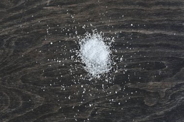 Mutfak tahtasına dağılmış beyaz tuz yığını. Boşluğu koyu bir arkaplanda kopyala.