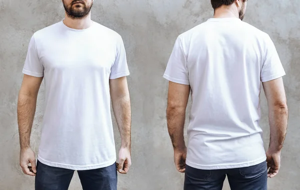 Boş beyaz tişörtlü, sakallı genç bir adam. Açık gri beton duvarın arka planında ön ve arka plan. Erkek tişörtü şablonu tasarımı ve yazdırma düzeni.