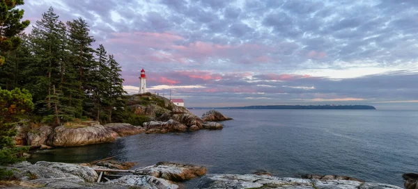 Lighthouse Park em uma costa rochosa durante um pôr do sol nublado dramático. — Fotografia de Stock