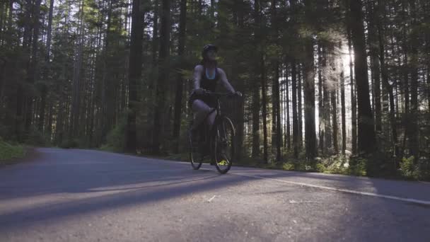 Mujer aventurera paseando en bicicleta por un sendero en el bosque — Vídeo de stock