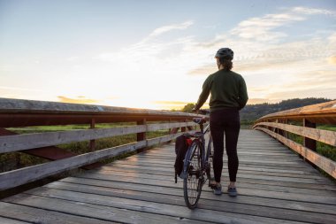 Tahta bir köprüde bisikleti olan beyaz beyaz beyaz beyaz kadın.