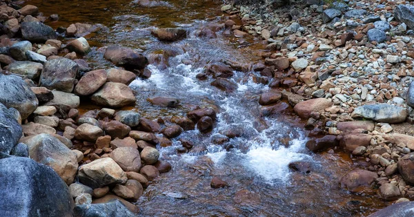 Voda tekoucí po řece kolem skal. — Stock fotografie