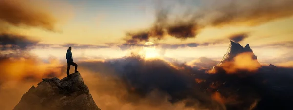 Dramatischer Blick auf abenteuerlustigen Mann, der auf einem felsigen Gipfel steht — Stockfoto