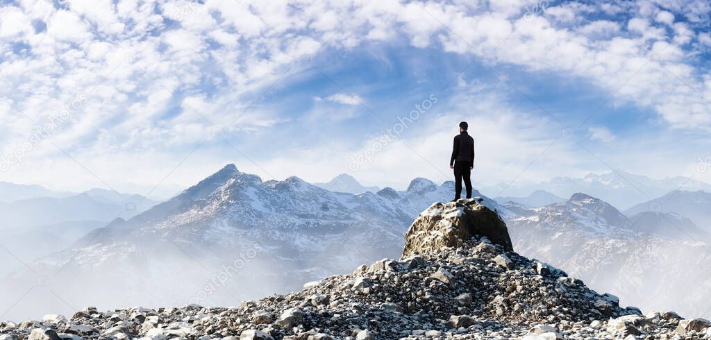 Adult Hiker Male standing on top of a rocky mountain overlooking the nature scene