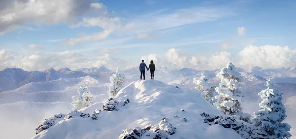 Adult man and woman holding hands on top of a snow peak. — Foto Stock