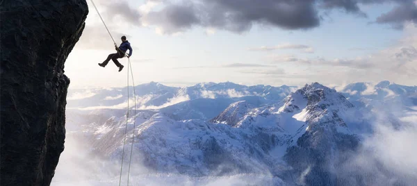 Adult adventurous man rappelling down a rocky cliff. — Stock Photo, Image