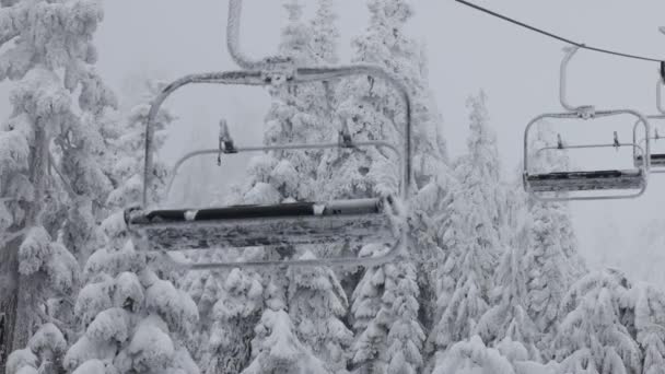 Sessellift im Skigebiet mit weißem Schnee bedeckt an einem verschneiten Wintertag. — Stockvideo