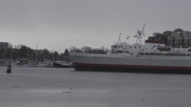 Gemi yağışlı kış günbatımında Victoria Limanı 'na geliyor.