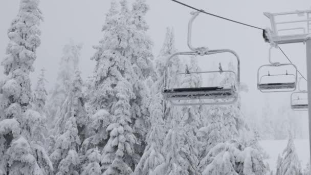 Chairlift no resort de esqui coberto de neve branca durante um dia de temporada de inverno nevado. — Vídeo de Stock