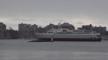 Gemi yağışlı kış günbatımında Victoria Limanı 'na geliyor.